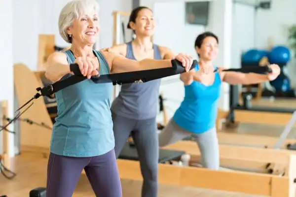 Toning Arms After 60: Empowering Womens Fitness Through Effective Weight Training 2 older woman doing weight training Westcliff-on-Sea and resistance in the gym to tone upper arms